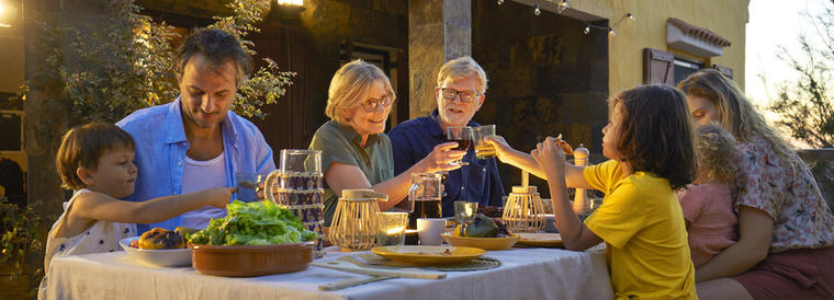 Reserva una casa rural en Frigiliana para disfrutar con toda la familia - Descripción de foto: familia reunida en torno a una mesa, cenando a la luz de bombillitas.